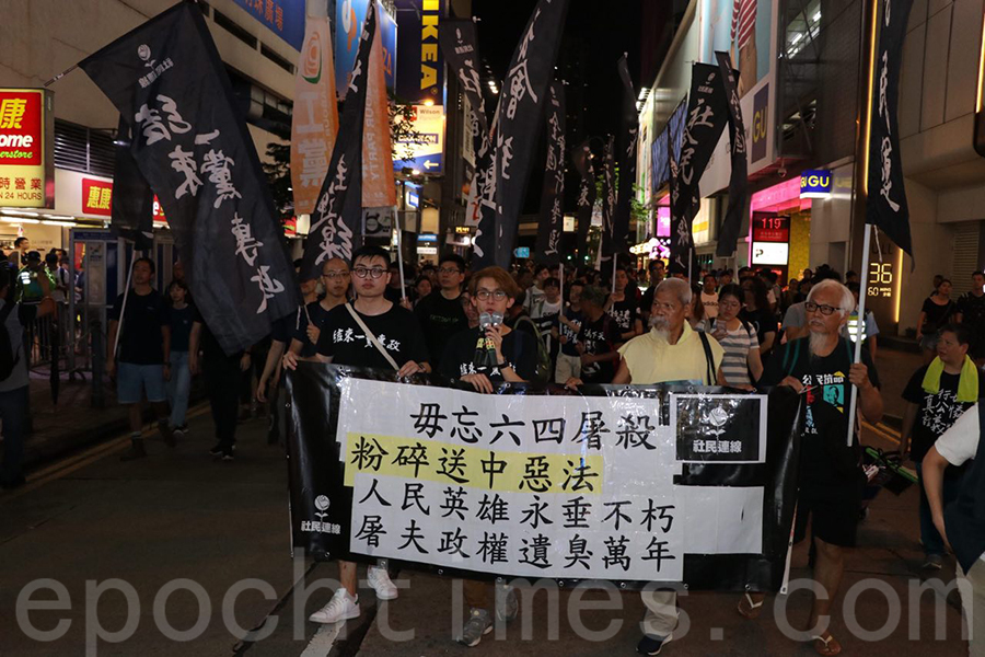 有市民拿着寫上「毋忘六四屠殺」等標語遊行到中聯辦門前。（蔡雯文／大紀元）