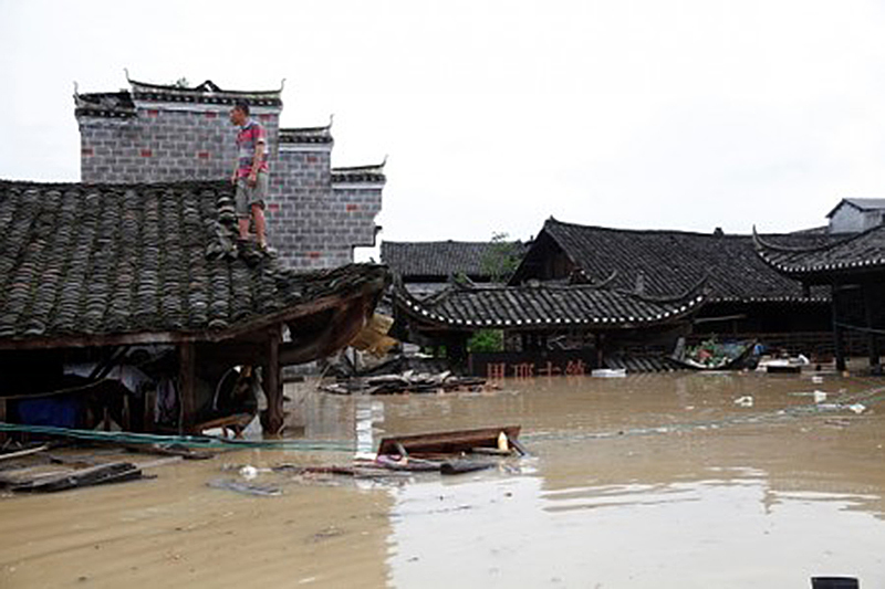 6月21日，湖南省龍山縣一名男子站在淹水的屋頂避難。（STR/AFP/Getty Images)