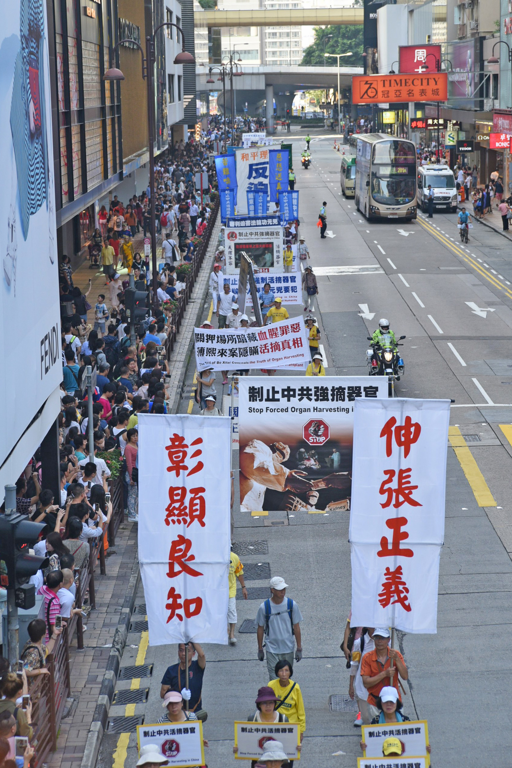 法輪功學員舉辦反對活摘遊行，在深水埗楓樹街球場開始遊行到尖沙咀，途中經過鬧區吸引許多民眾觀看。圖為集會中新唐人旗鼓隊表演。（文瀚林/大紀元）