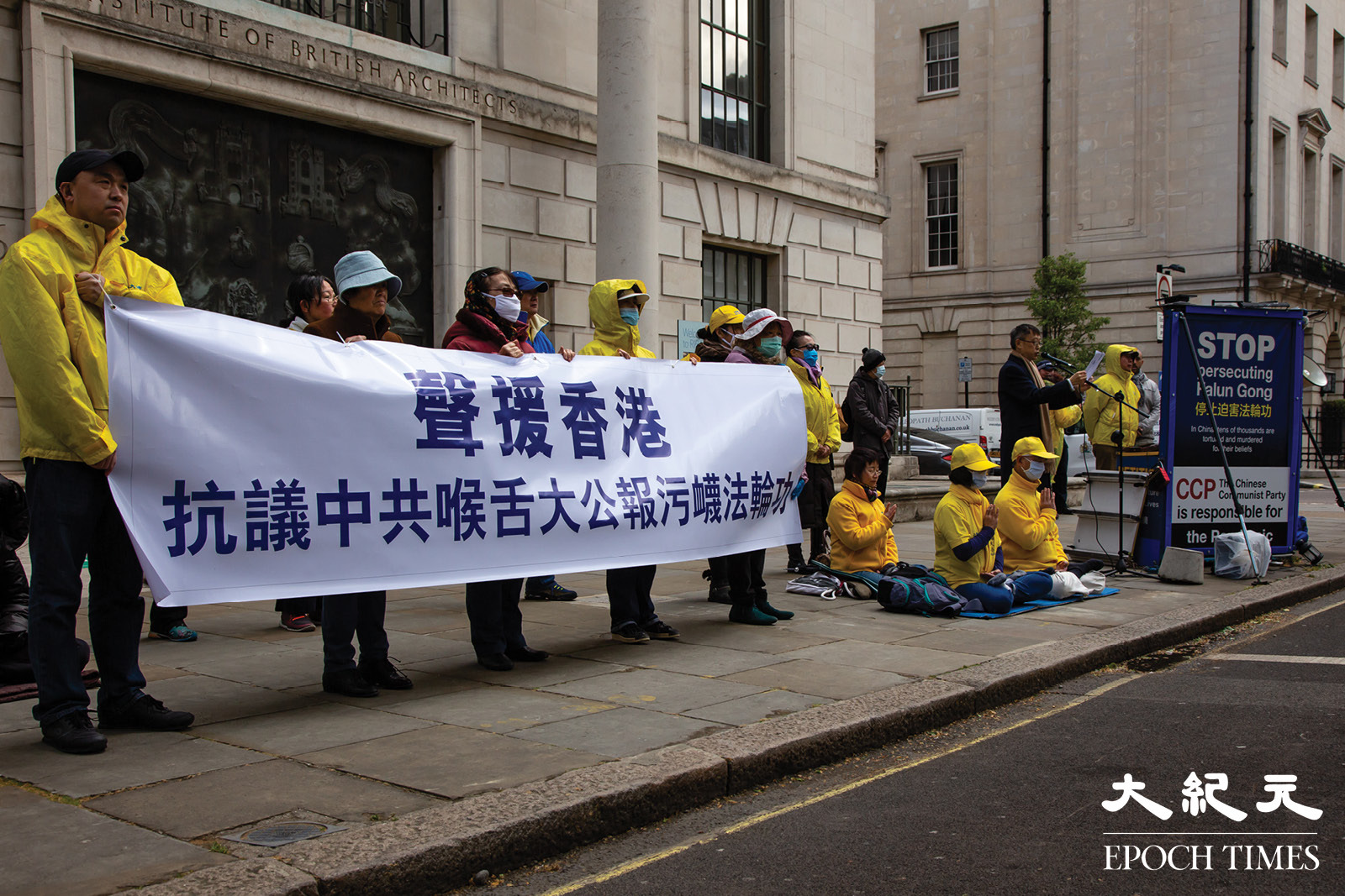 5月4日，英國法輪功學員在倫敦中領館對面舉行集會，舉起「聲援香港 抗議中共喉舌大公報誣衊法輪功」的橫幅。（羅元／大紀元）