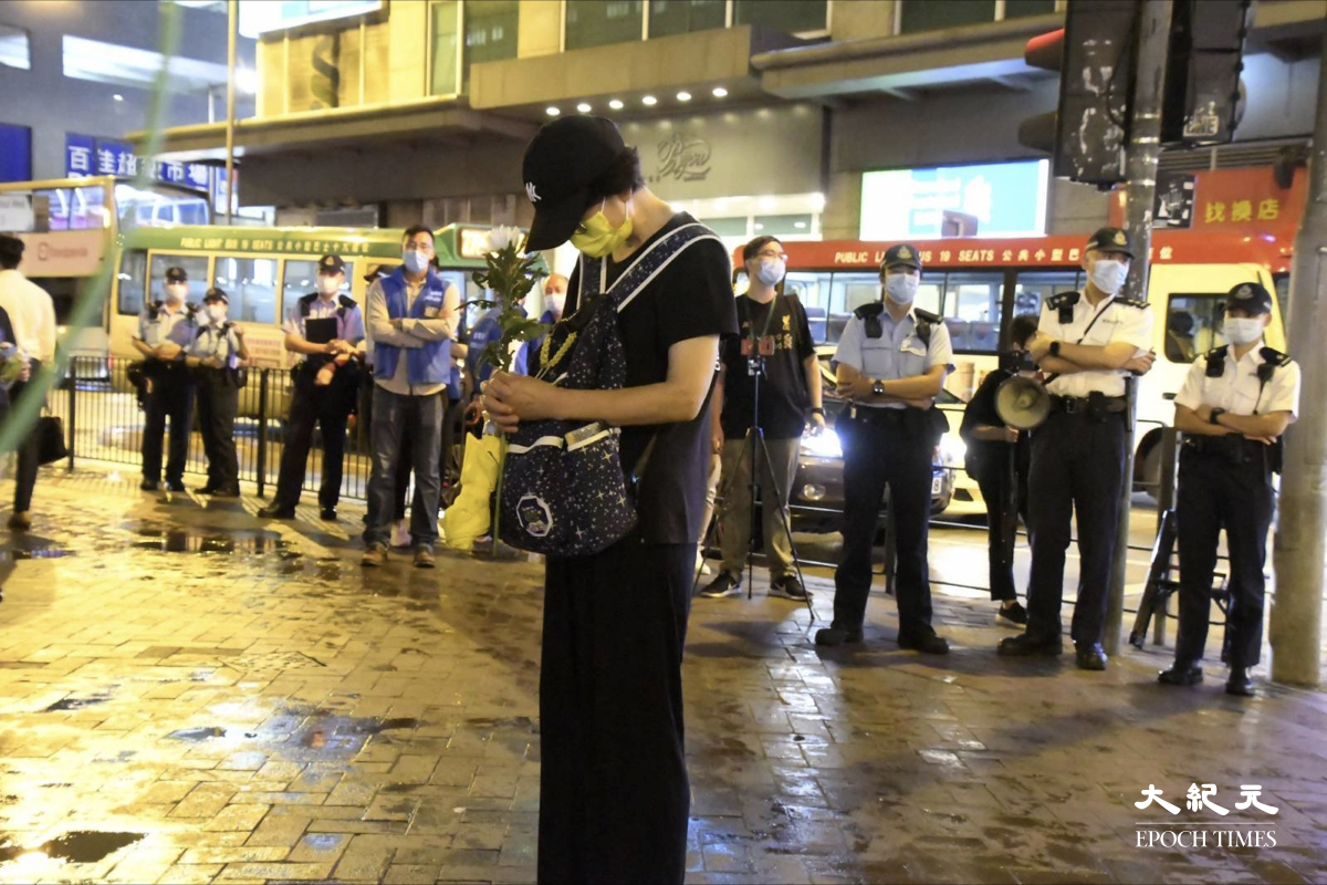 縱使當局禁止，縱然身後有大批警察在場，一名女子仍然堅持手持鮮花在太子站外悼念。（麥碧/大紀元）