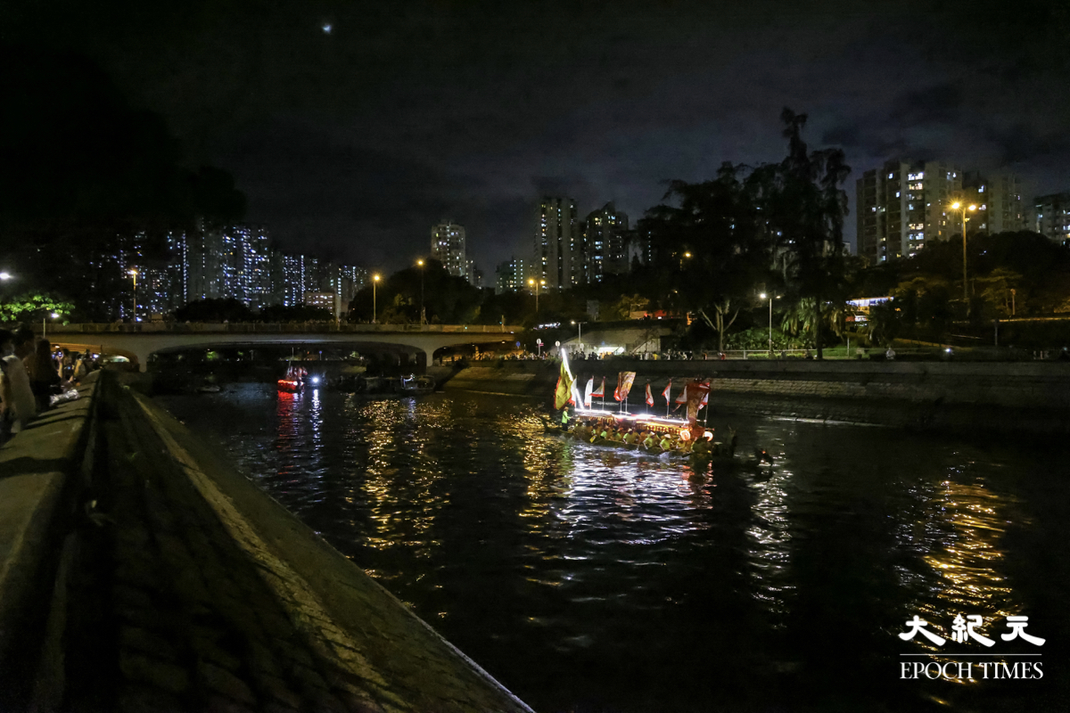 兩艘分別來自大埔鍾氏穎川堂及香港石氏宗親傳統夜龍總會的龍舟，亮起燈光來回在漆黑的林村河上巡遊。（陳仲明／大紀元）