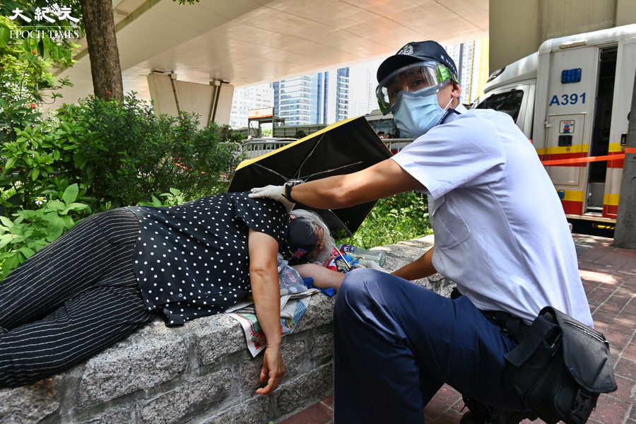 蘋果高層張劍虹及羅偉光，19日上午在西九龍裁判法院提堂，王婆婆王鳳瑤在法院外示威時被警察抬走，及後感動不適被救護車送往醫院。（宋碧龍／大紀元）