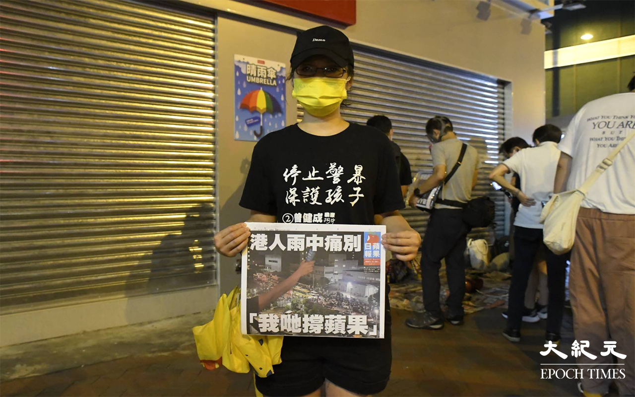 一名女子於旺角購買《蘋果日報》後給傳媒拍照。（麥碧 / 大紀元）