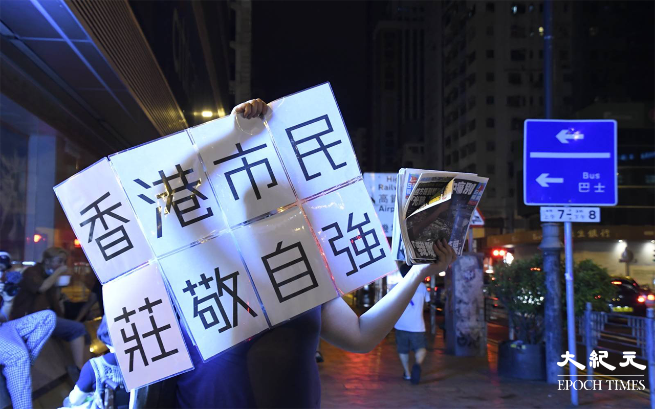 一名市民購買《蘋果日報》後，手持自己製作的標語，給傳媒拍照。（麥碧 / 大紀元）