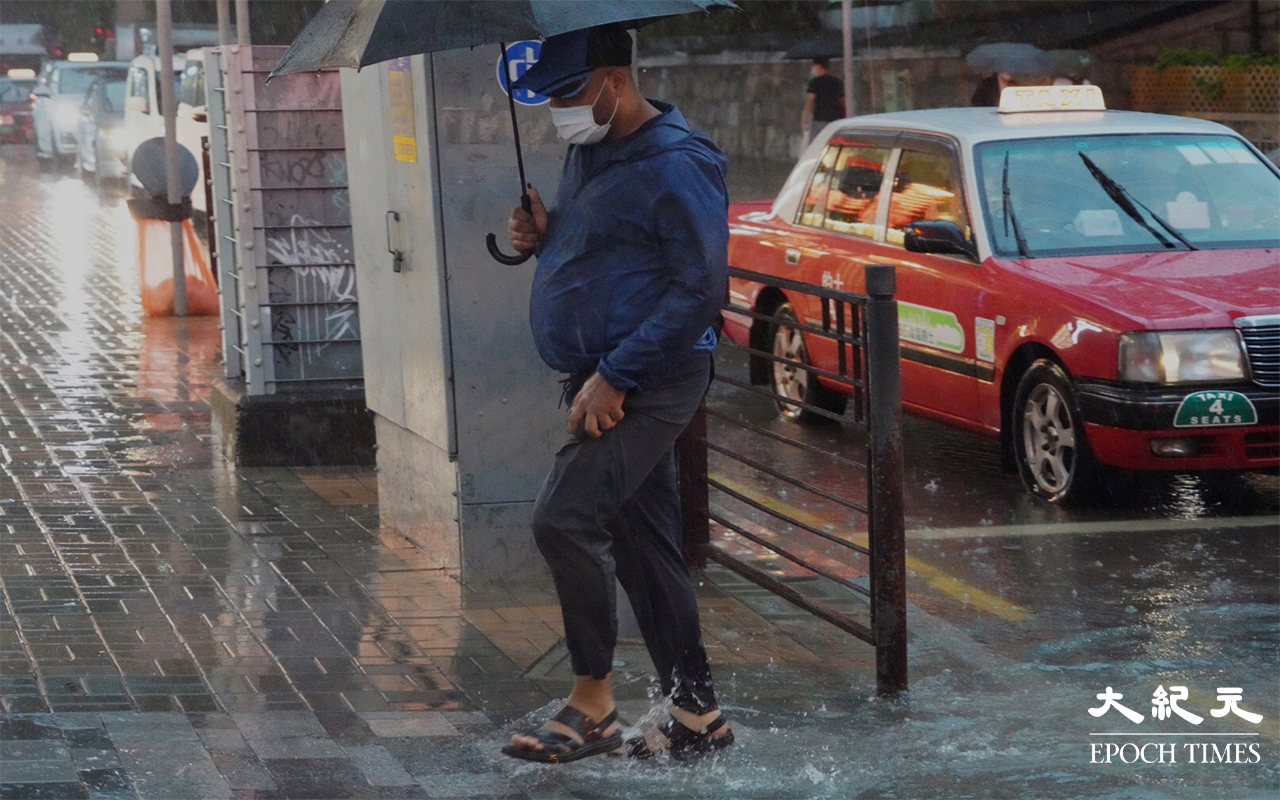 行人冒雨前行。（余鋼／大紀元）