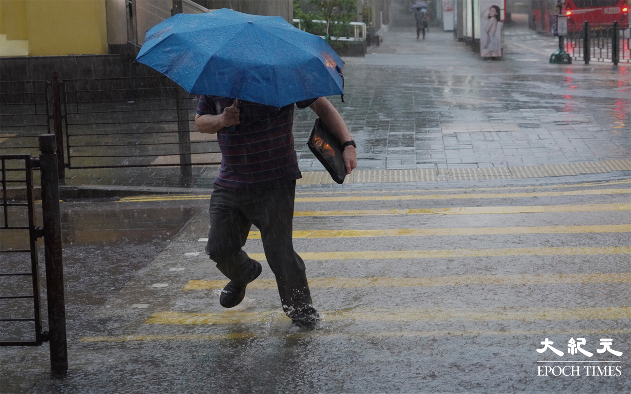 行人在雨中前行。（余鋼／大紀元）