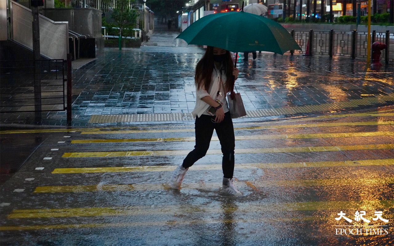 行人在雨中前行。（余鋼／大紀元）