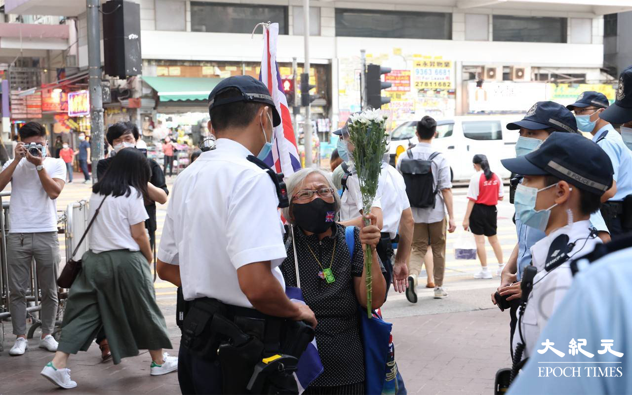 下午6時許，王婆婆在太子站外手持英國國旗及白色鮮花出現，在場警員見狀相當緊張。(李辰 / 大紀元）