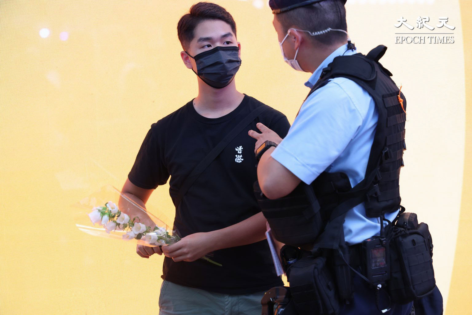 大市民手持白花，穿黑衣在事發位置悼念遭警員截查。（李辰／大紀元）