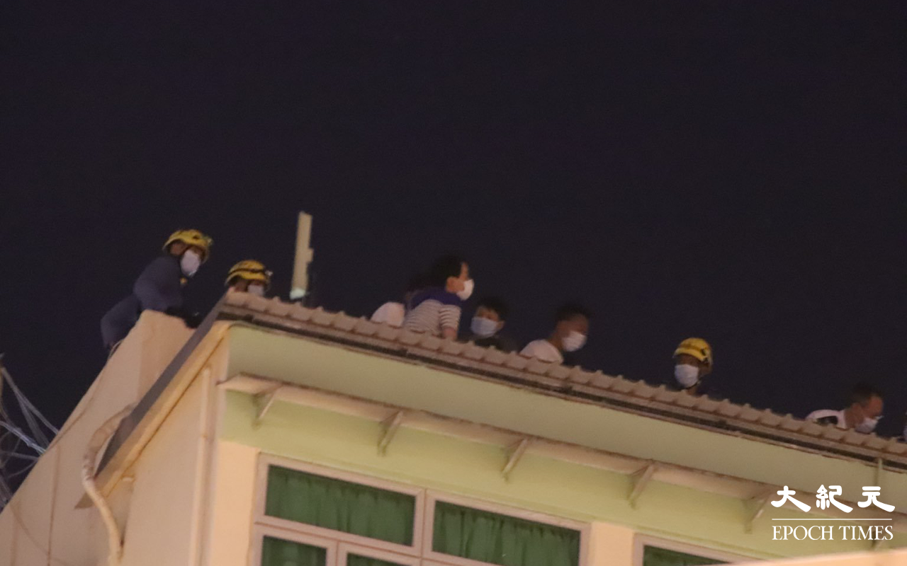 消防員於天台向該名危坐男子進行遊說。（麥碧 / 大紀元）