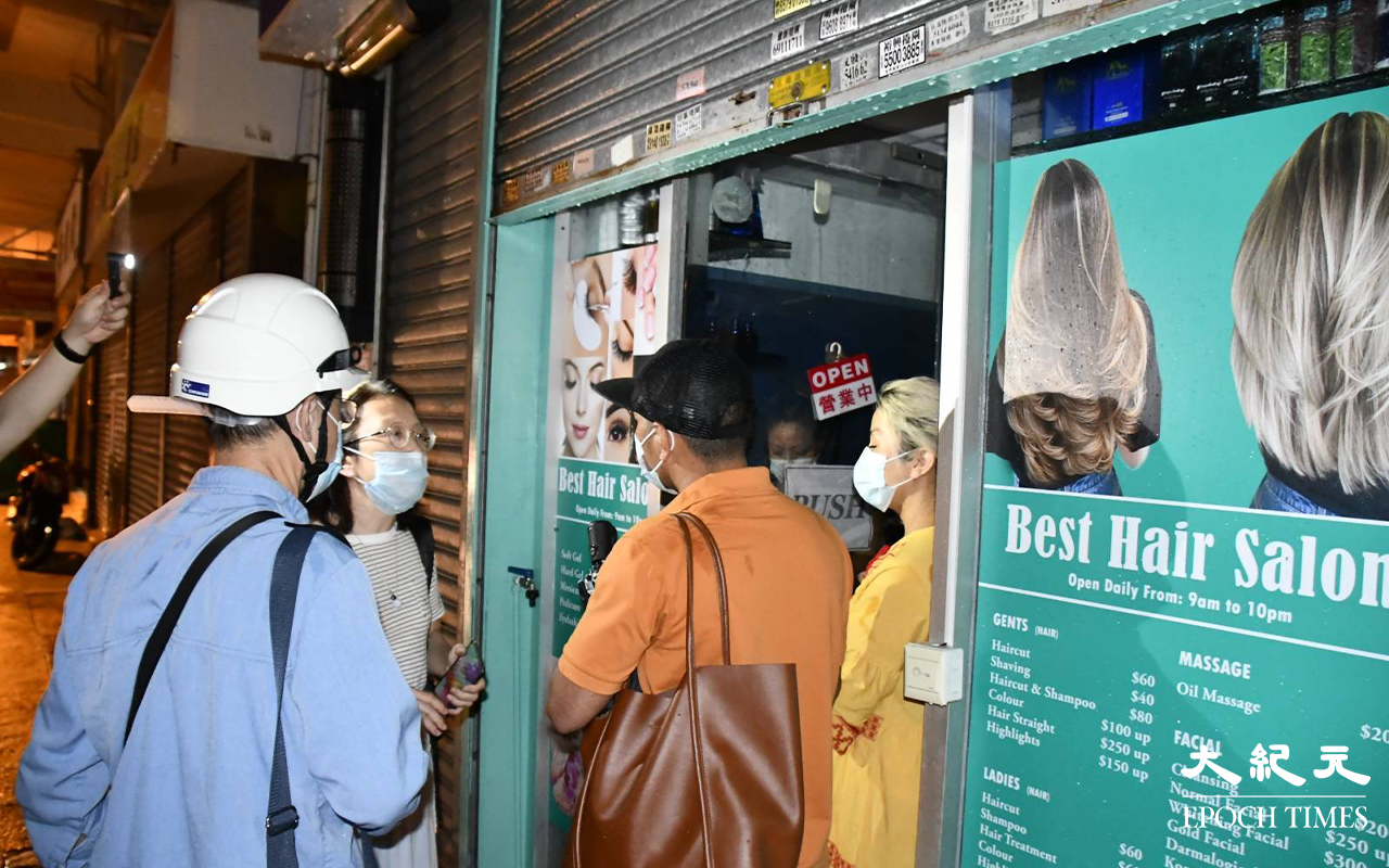 前油尖旺區議員朱慧芳及中電職員，向尼泊爾籍店主講解情況。（李辰 / 大紀元）