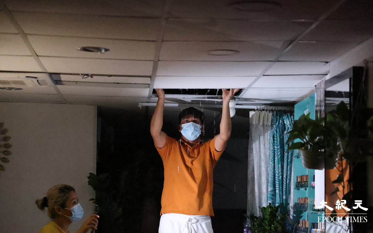 火警救熄後，地面鋪頭出現水浸情況，尼泊爾籍負責人一家在清理現場。（李辰 / 大紀元）