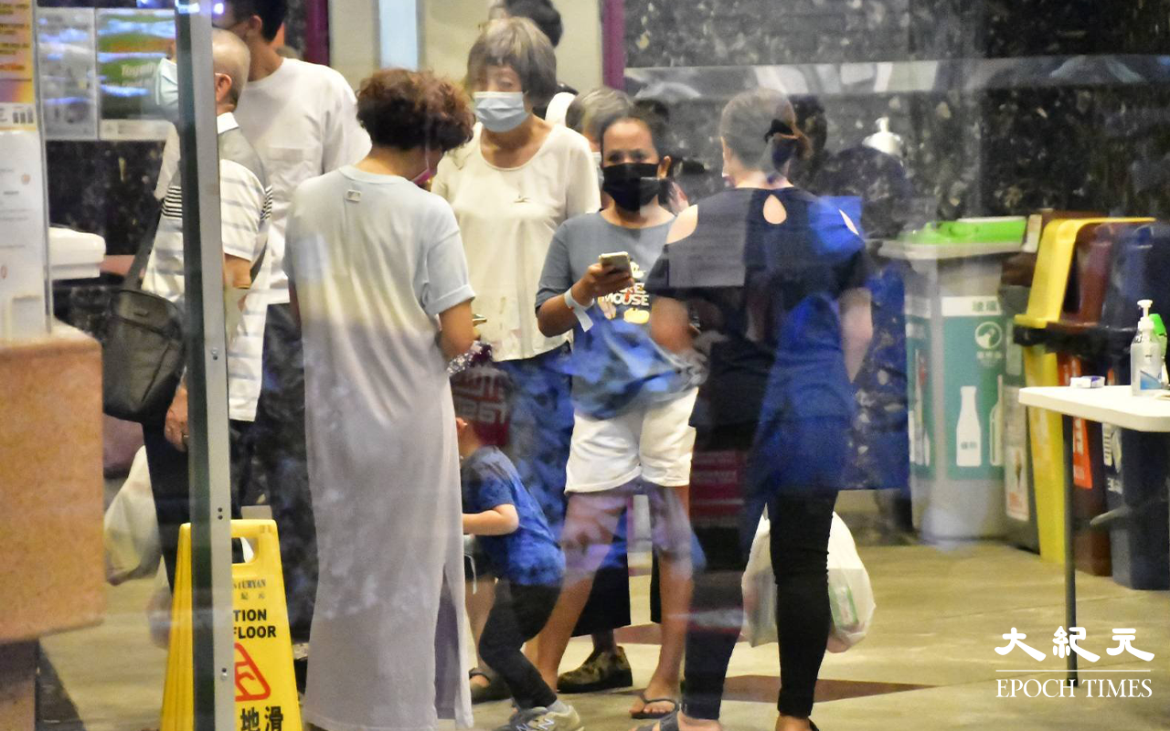 穿著保護衣裝備的工作人員，在大廈電梯大堂內為住客登記。（麥碧／大紀元）