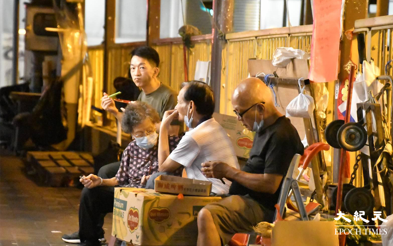 「均香餅家」上下，忙完一日終於可以坐在餅店對開的行人隧道旁，休息一下吃晚飯。（麥碧／大紀元）
