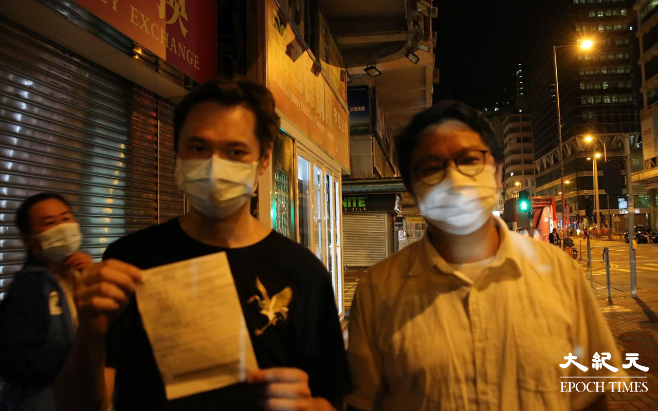 油尖旺區議員朱江瑋，與一名參與電影放映會被票控的市民，接受記者拍照。（李辰／大紀元）