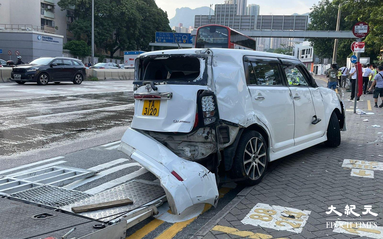 涉事的白色私家車，左邊車頭損毀、擋風玻璃碎裂、車尾泵把被撞至飛脫，私家車調頭停在龍翔道上，男司機和女乘客，分別送往聯合醫院及伊利沙伯醫院治理。（卓相如／大紀元）