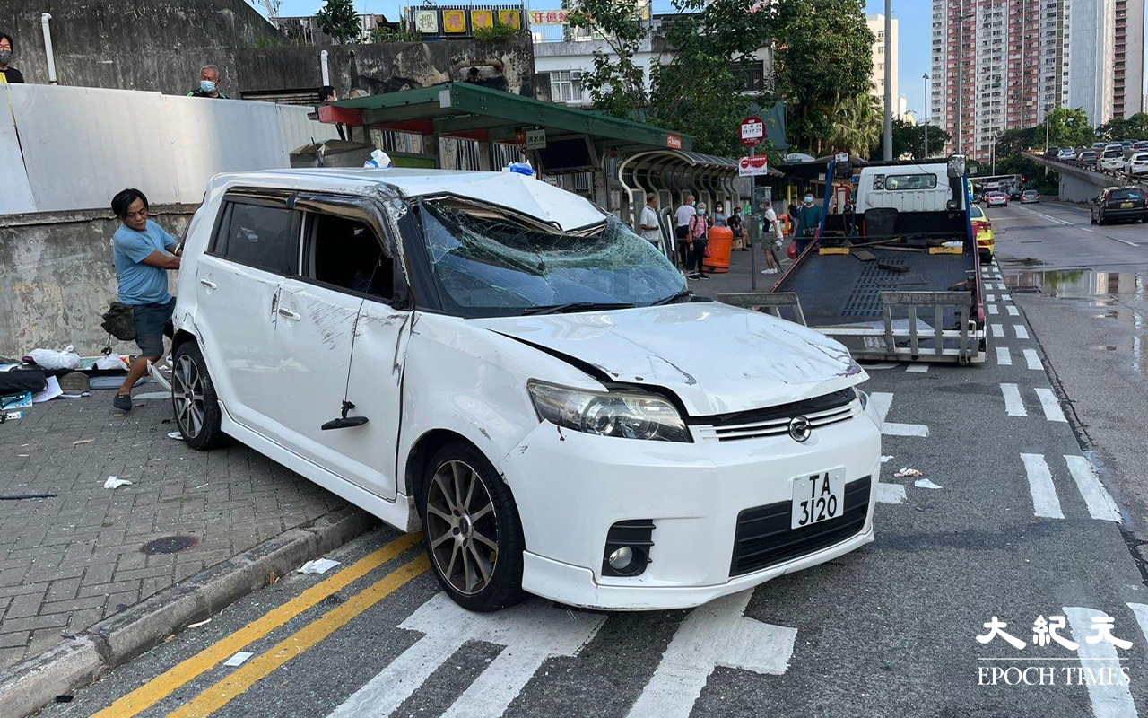 涉事的白色私家車，左邊車頭損毀、擋風玻璃碎裂、車尾泵把被撞至飛脫，私家車調頭停在龍翔道上，男司機和女乘客，分別送往聯合醫院及伊利沙伯醫院治理。（卓相如／大紀元）