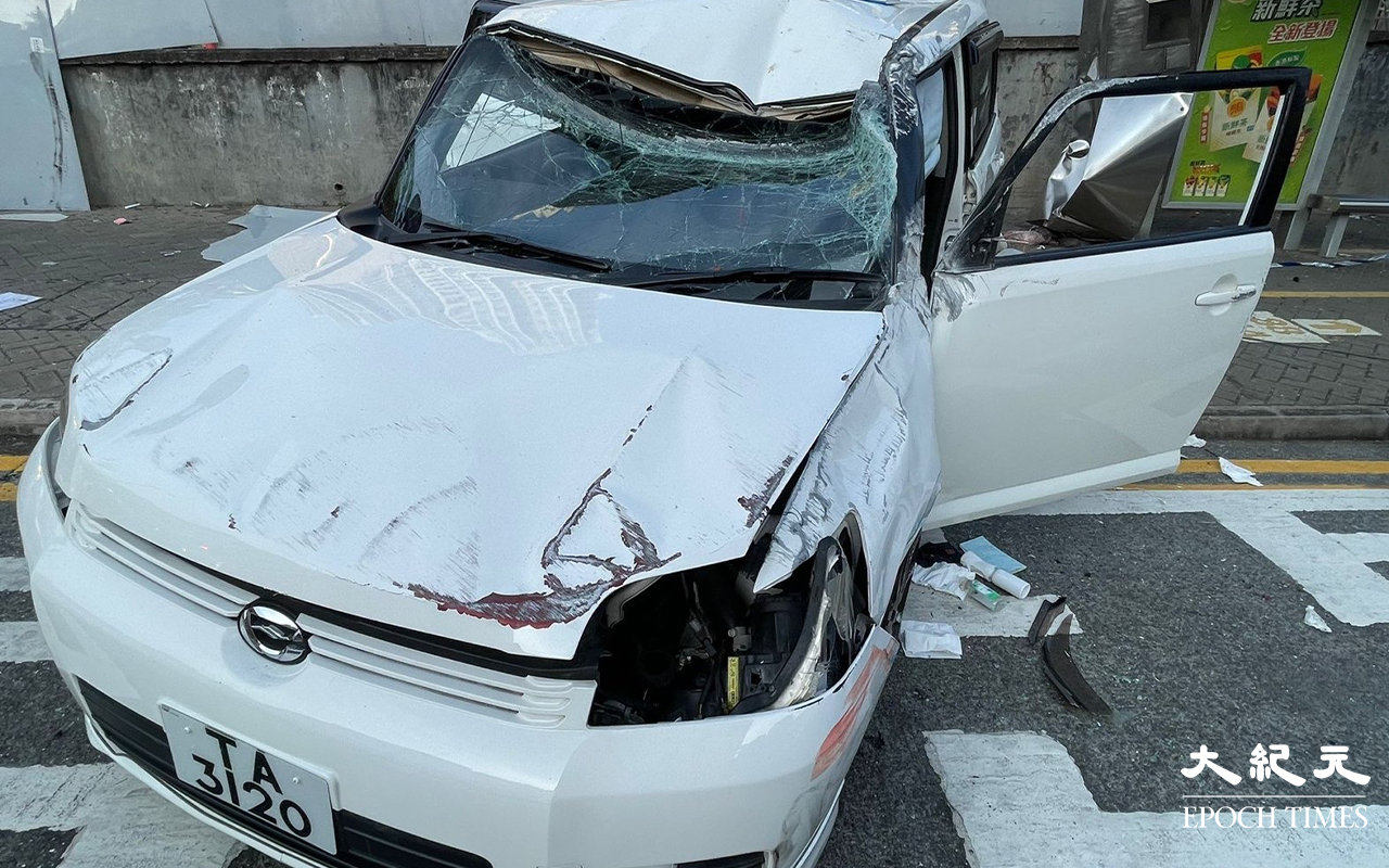 白色私家車，左邊車頭損毀、擋風玻璃碎裂、私家車調頭停在龍翔道上，男司機和女乘客，分別送往聯合醫院及伊利沙伯醫院治理。（卓相如／大紀元）