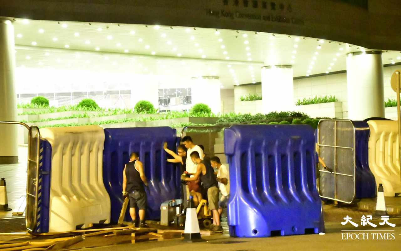 今日 (30日) 凌晨一時許，陸續有貨車將水馬運抵港灣道會展舊翼出入口，工人在架設水馬。（麥碧／大紀元）