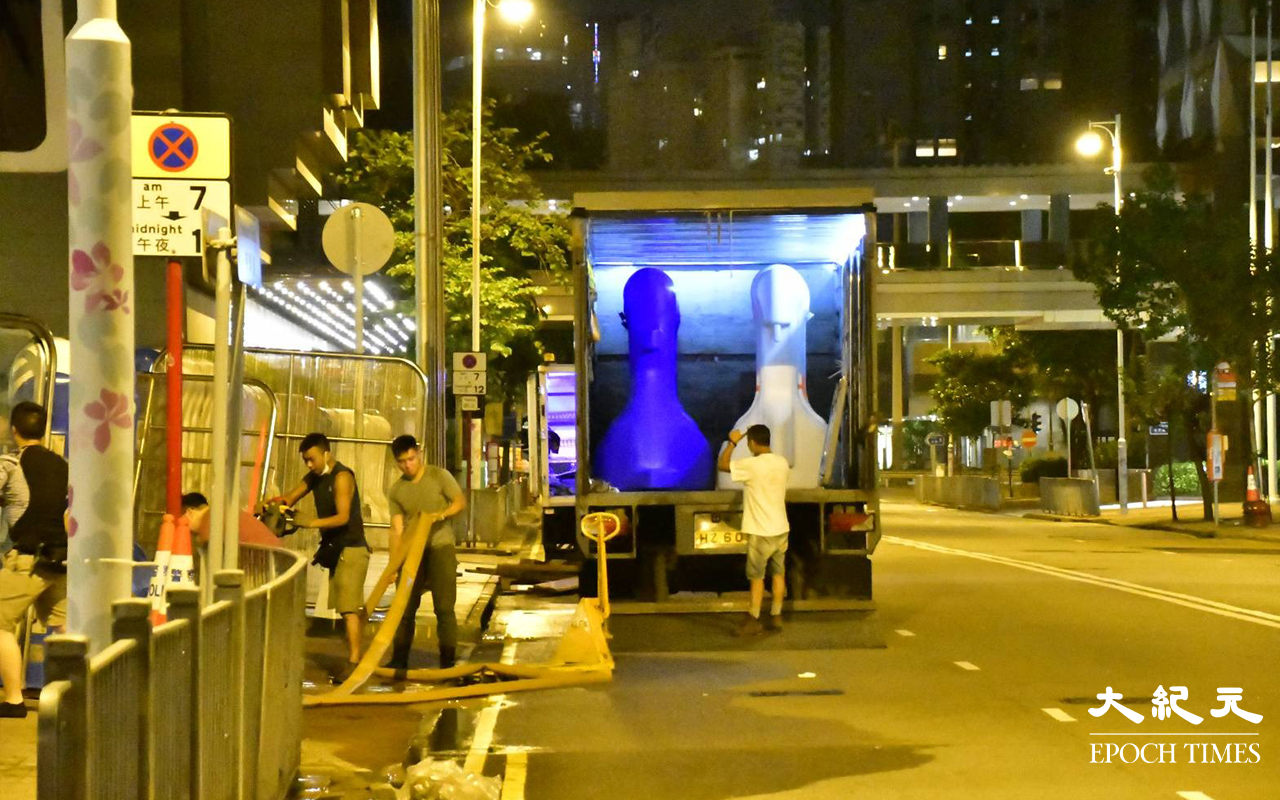 今日 (30日) 凌晨一時許，陸續有貨車將水馬運抵港灣道會展舊翼出入口，工人在架設水馬。（麥碧／大紀元）