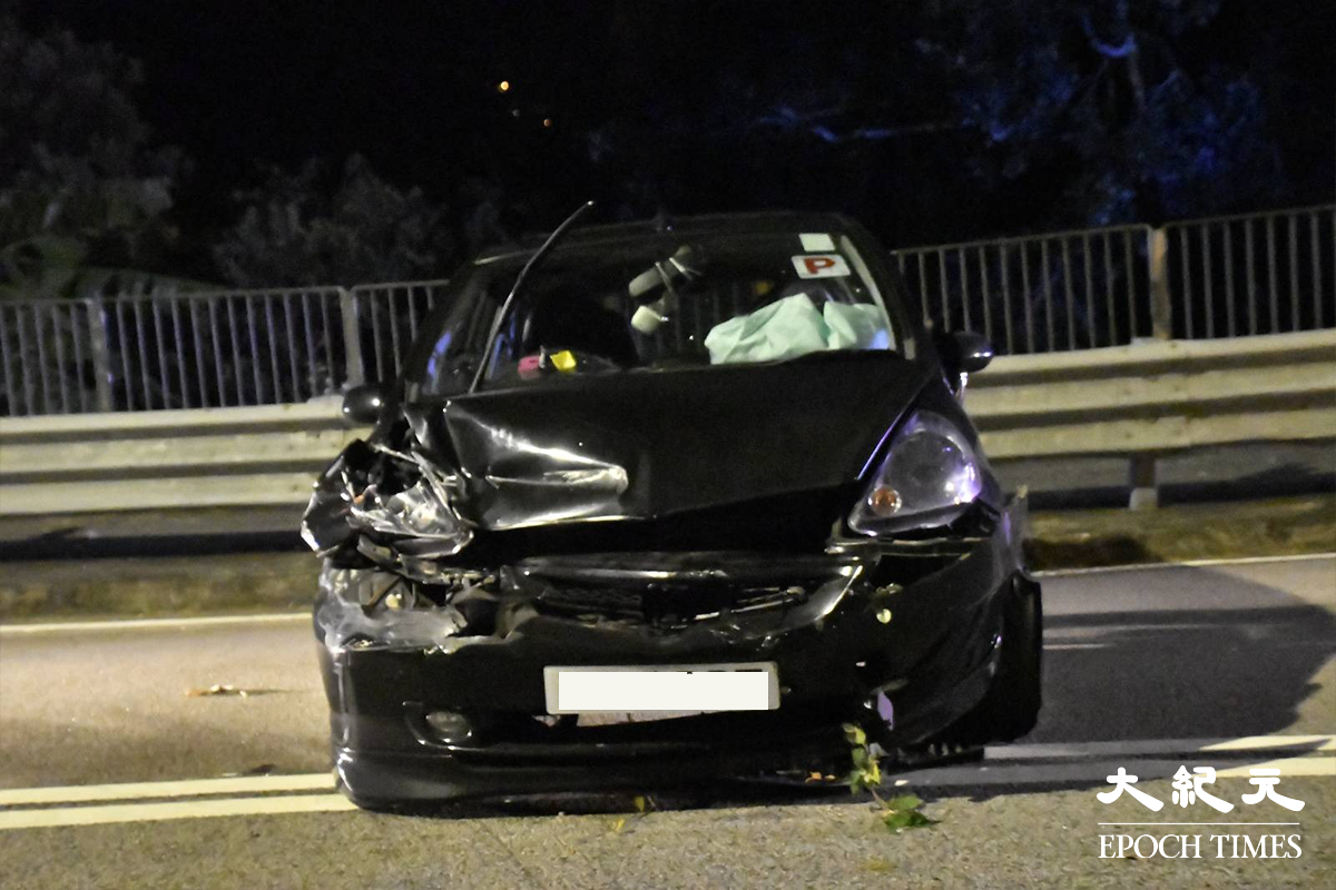 掛有P牌的黑色私家車，失控撞毀鐵欄後反彈回路面，橫放在一條行車線上，車頭嚴重損。（麥碧／大紀元）