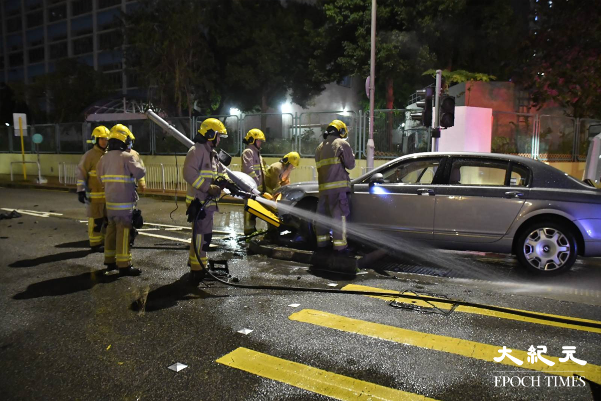 由於涉事私家車意外後車尾冒出白煙，消防到場後，開動一條喉向涉事車輛射水戒備。（麥碧／大紀元）