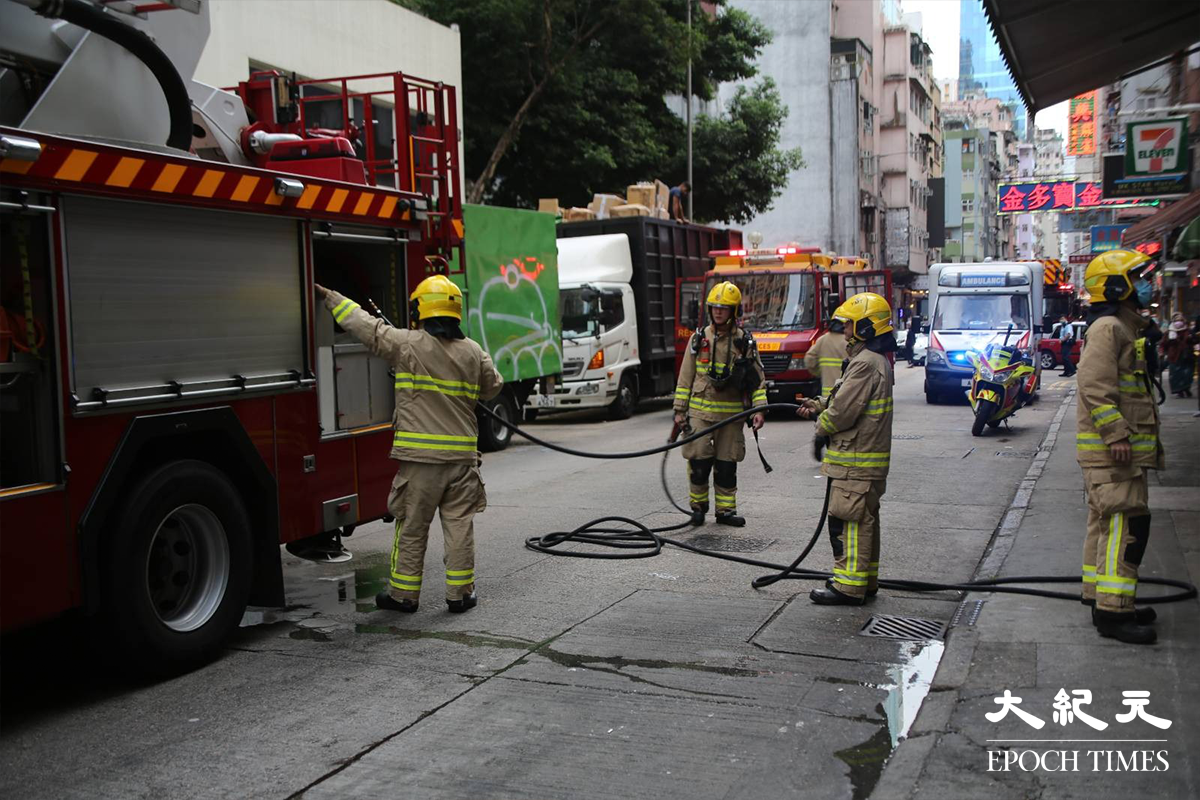 消防接報後隨即派出5輛消防車及1輛救護車趕抵現場，有消防員攜帶手提滅火裝備，進入大廈後樓梯電錶房位置。（金國米／大紀元）