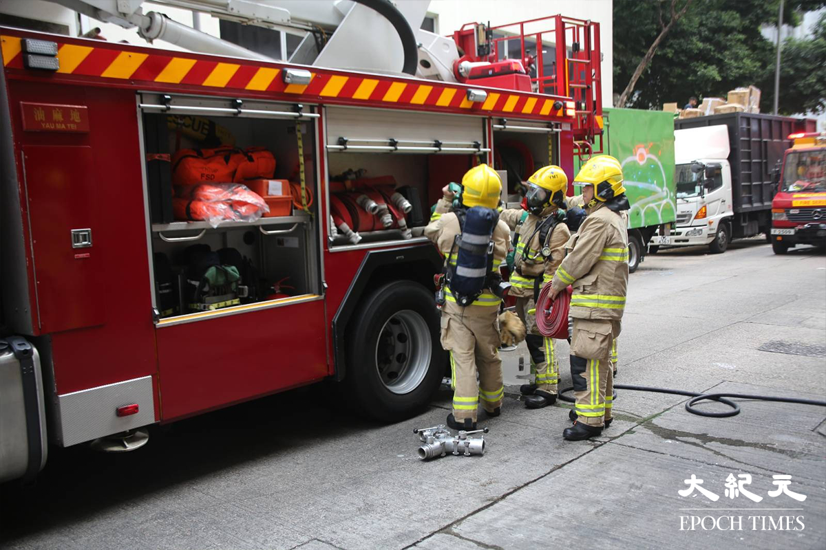 消防接報後隨即派出5輛消防車及1輛救護車趕抵現場，有消防員攜帶手提滅火裝備，進入大廈後樓梯電錶房位置。（金國米／大紀元）