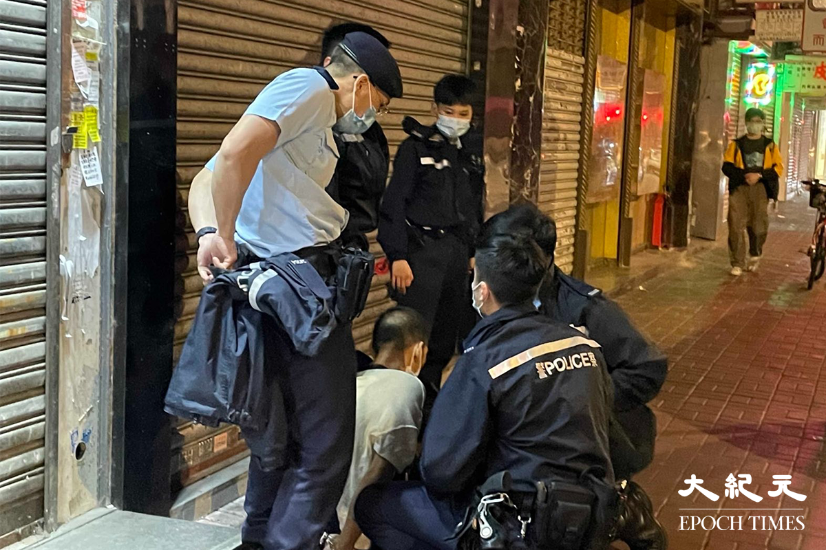 一名年約40歲的男子，被警方在其身上搜出少量懷疑海洛英，在場警員隨即將其鎖上手銬，並帶返旺角警署通宵扣查。（卓相如／大紀元）