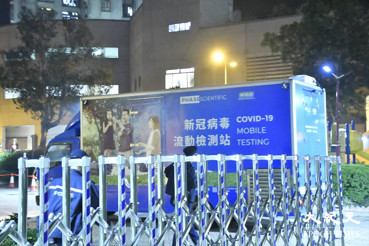 政府於晚上7時30分刊憲圍封強檢安禧閣後，陸續有流動檢測車及物資貨車進入圍封範圍。鋼閘內就是，今晚被圍封強檢的屯門兆禧苑安禧閣。（麥碧／大紀元）