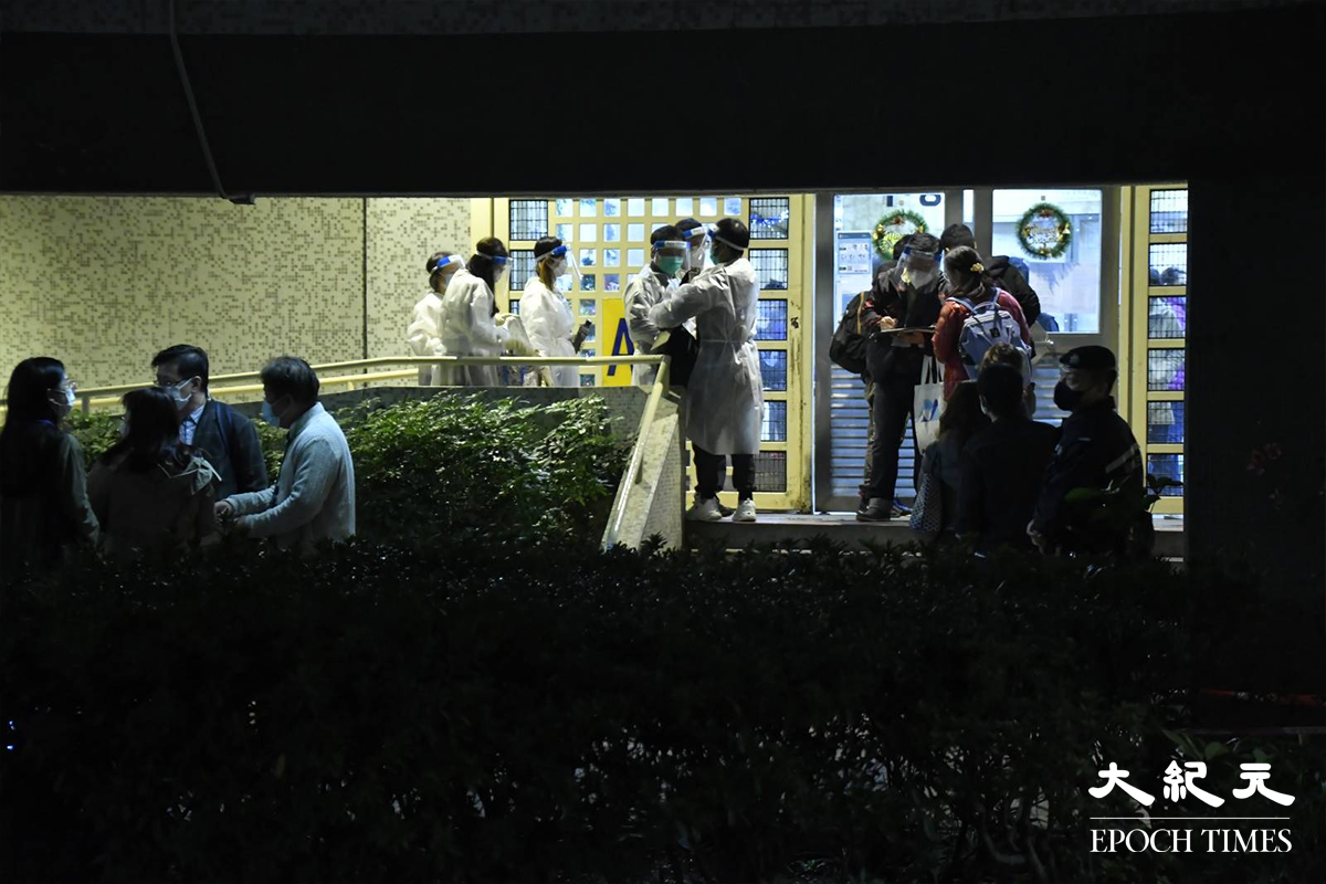 晚上約8時，穿著全套保護裝備的工作人員準備進入，被圍封強檢的A座安禧閣。（麥碧／大紀元）
