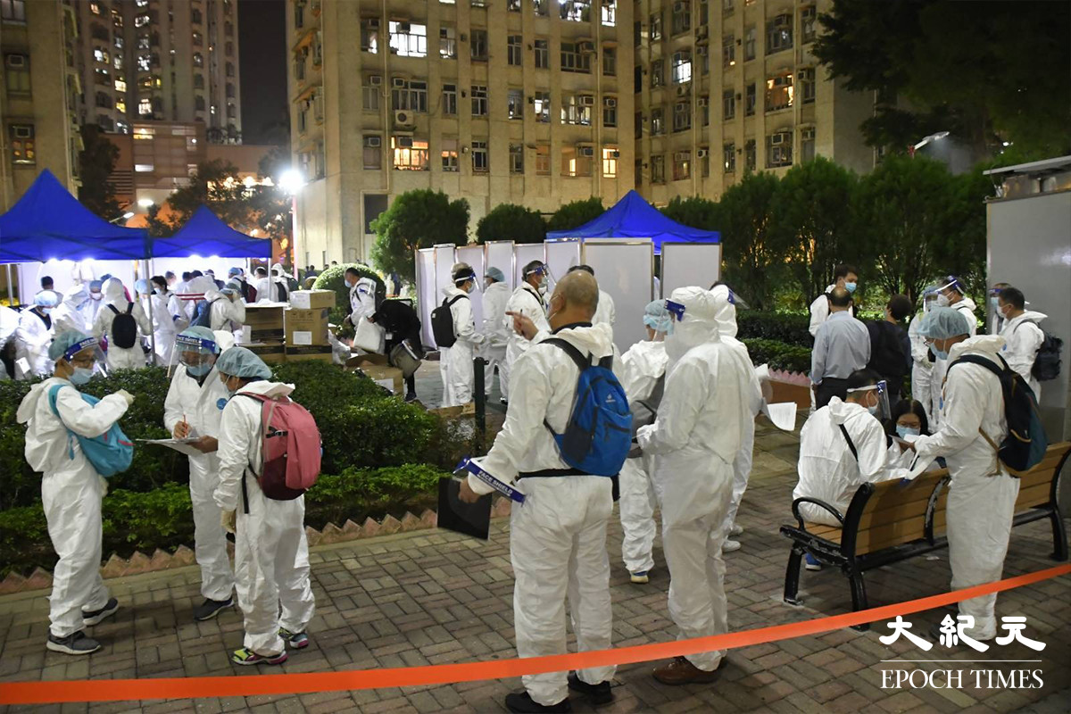 穿著全套保護裝備的工作人員於晚上8時35分，進入屯門兆禧苑A座安禧閣洗樓。（麥碧／大紀元）