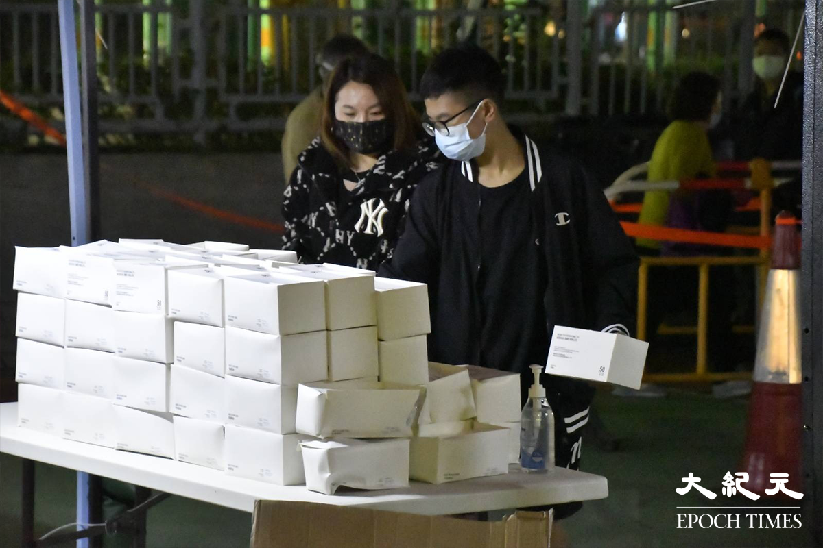 晚上9時15分，已完成檢測的居和樓居民，被安排到物資站自行領取物之後，排隊等候返回家中。（麥碧／大紀元）