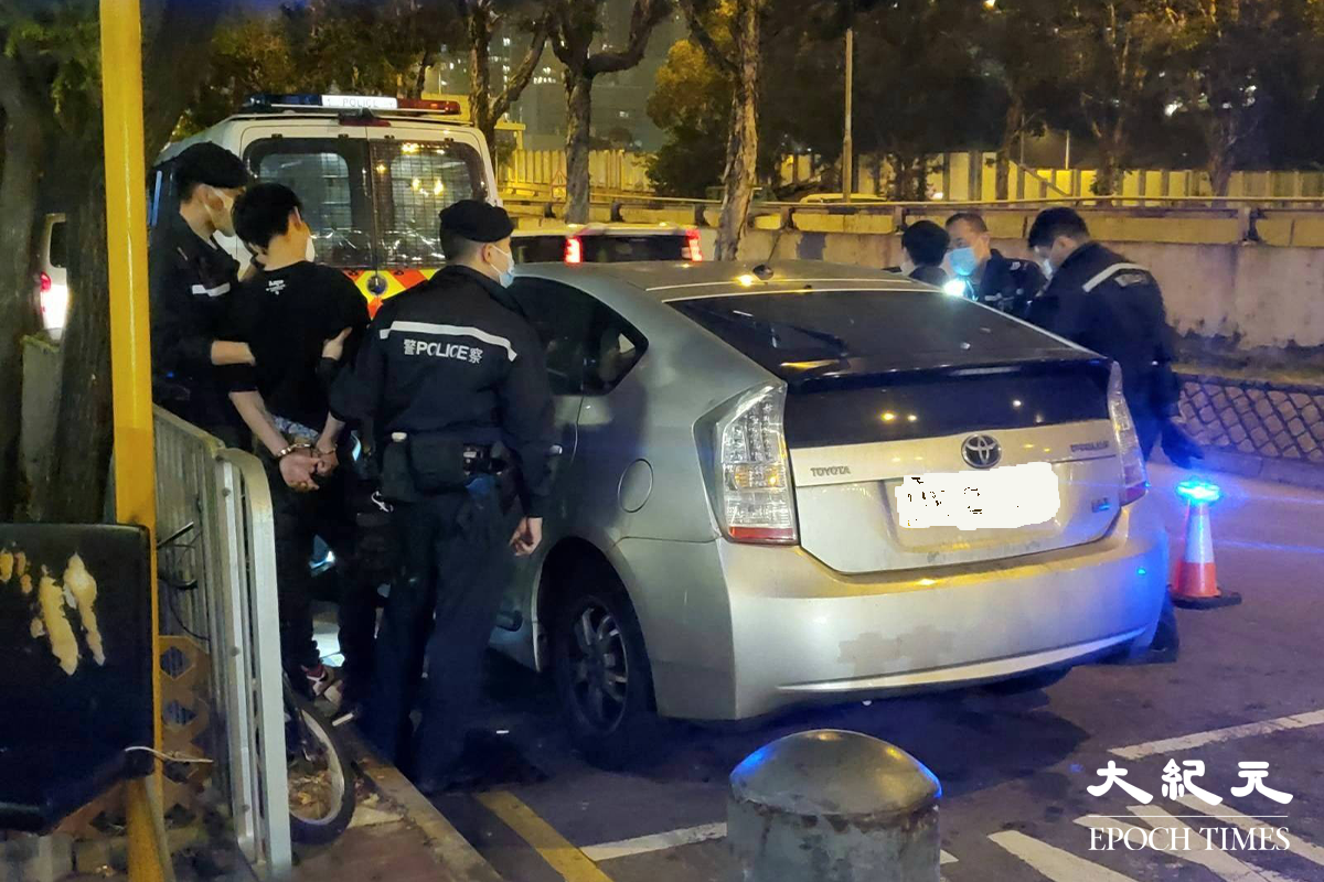 警方將涉嫌販毒的疑犯，押返私家車旁協助搜查。（金國米／大紀元）