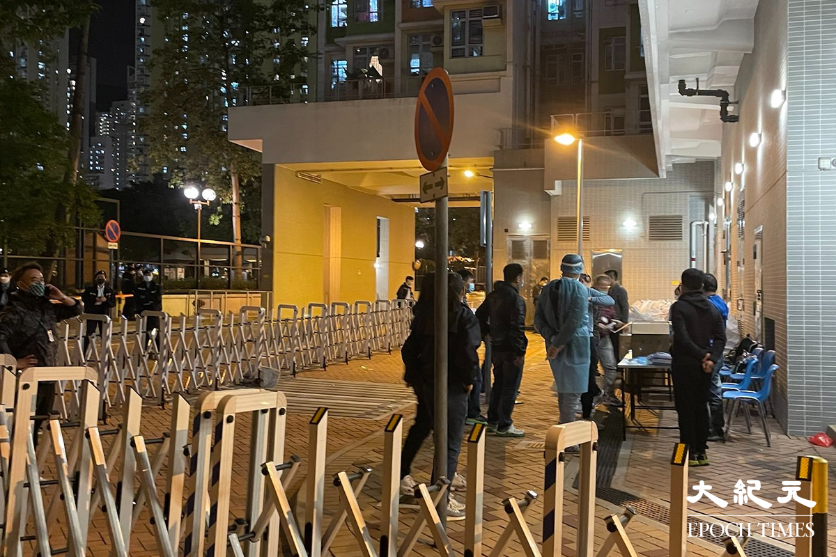 政府晚上7時54分刊登憲報後，大批工作人員進駐長沙灣邨長欣樓對開，有部分更已換上全套保護衣，為稍後居民強檢準備。（卓相如／大紀元）