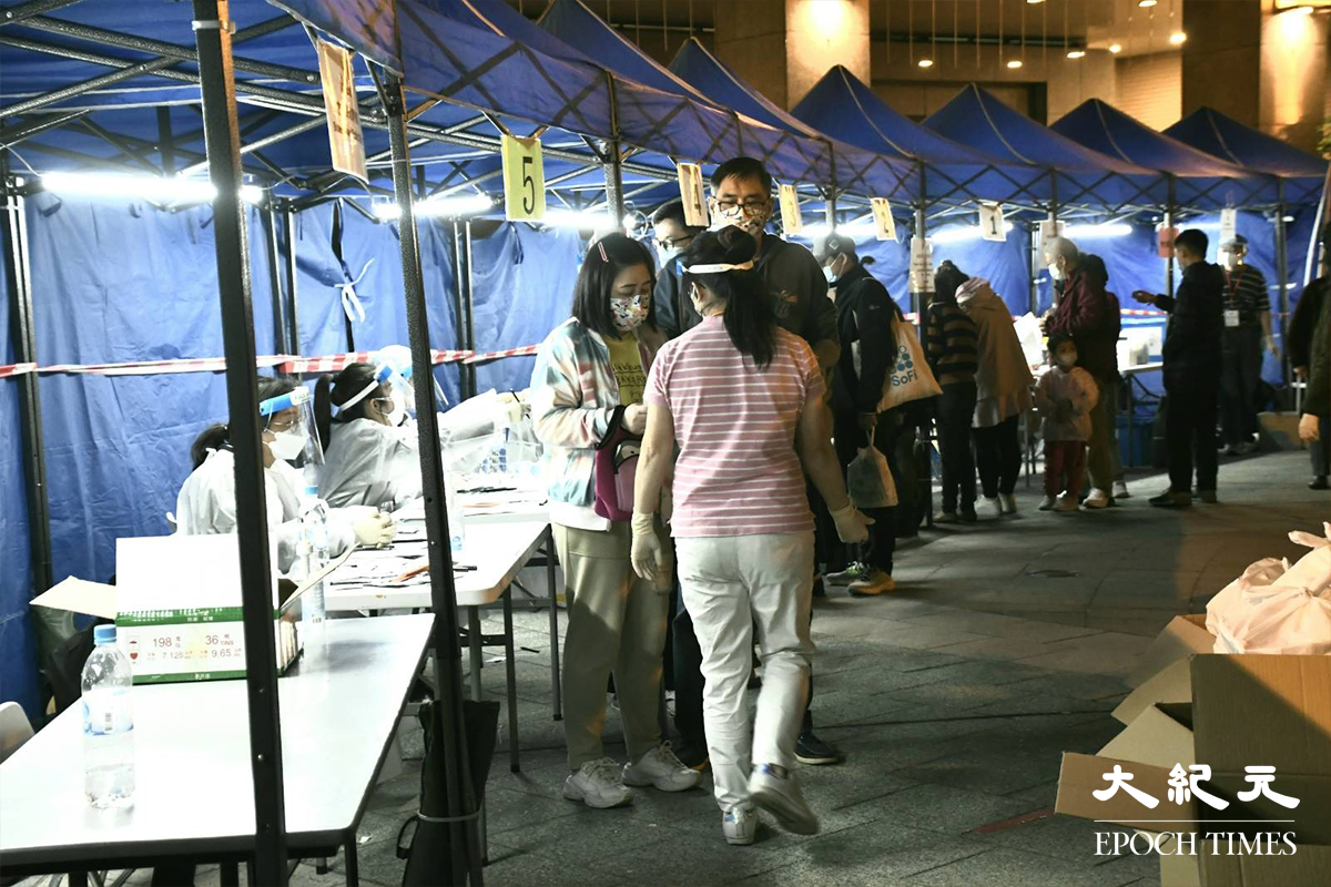 荃灣名逸居第1座居民於紅色帳篷接受檢測後，被安排到藍色帳篷登記，之後再到旁邊領取物資袋返回家中。（麥碧／大紀元）