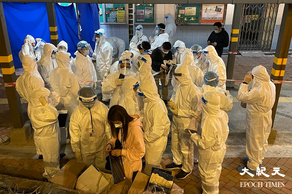晚上8時40分，彩雲邨長波樓外，已聚集大批穿著全套白色保護裝備的工作人員。（卓相如／大紀元）