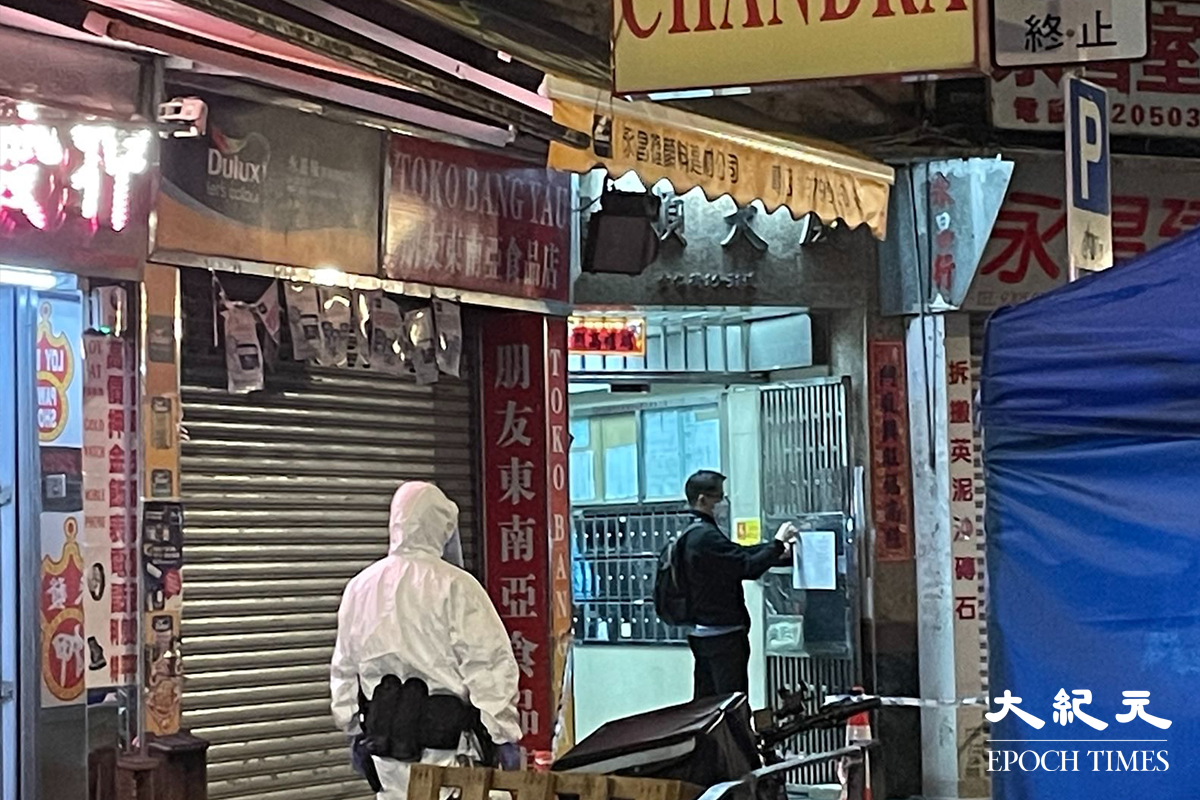 工作人員於晚上9時45分，在崇仁街安順大廈大門貼上圍封強檢之告示。（卓相如／大紀元）