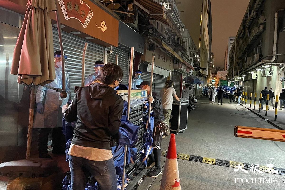 晚上7時35分，大批工作人員運送物資道隆基大樓D座大廈外。（卓相如／大紀元）