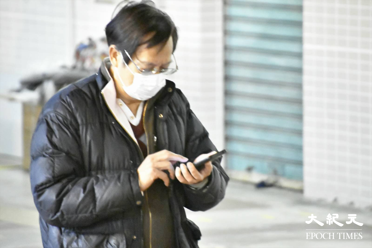 剛完成檢測的東滿樓居民，紛紛拿著手提電話查看自己的檢測結果。（麥碧／大紀元）