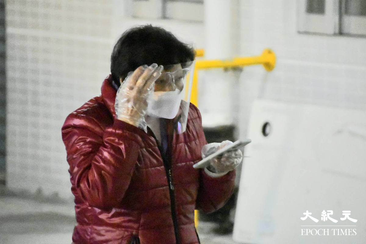 剛完成檢測的東滿樓居民，紛紛拿著手提電話查看自己的檢測結果。（麥碧／大紀元）