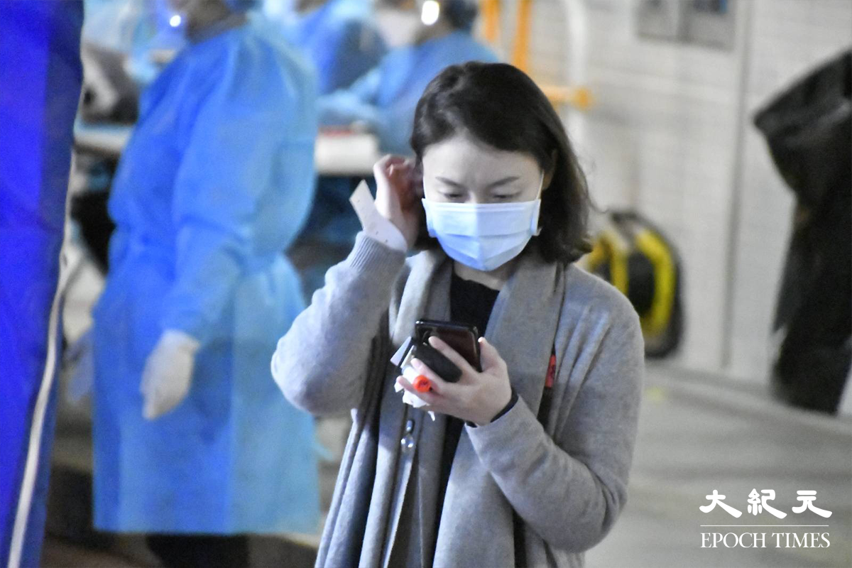 剛完成檢測的東滿樓居民，紛紛拿著手提電話查看自己的檢測結果。（麥碧／大紀元）