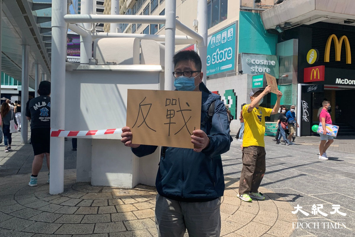 下午一時許，有兩人率先舉起標語，並高叫反戰口號。（唐健豐／大紀元）