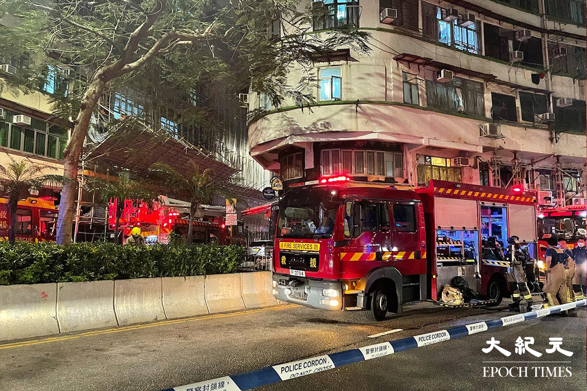 消防接報後派出多輛消防車趕抵現場，並隨即開動一條喉及派出兩隊煙帽隊進入火場灌救，警方將涉事大廈對開一段街道封閉。（卓相如／大紀元）