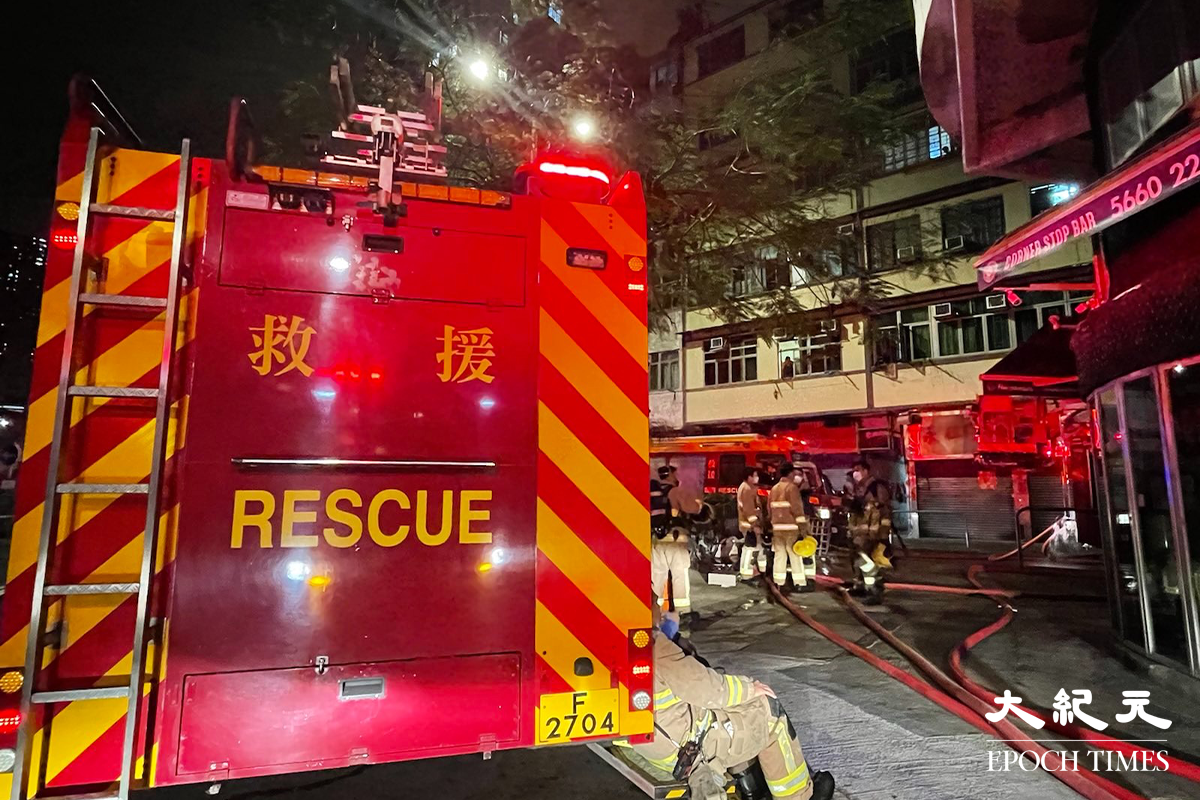消防接報後派出多輛消防車趕抵現場，並隨即開動一條喉及派出兩隊煙帽隊進入火場灌救，警方將涉事大廈對開一段街道封閉。（卓相如／大紀元）