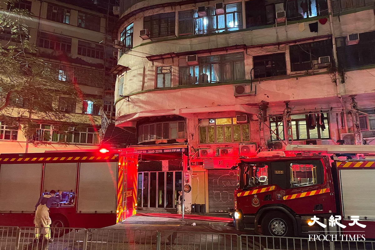 消防接報後派出多輛消防車趕抵現場，並隨即開動一條喉及派出兩隊煙帽隊進入火場灌救，警方將涉事大廈對開一段街道封閉。（卓相如／大紀元）