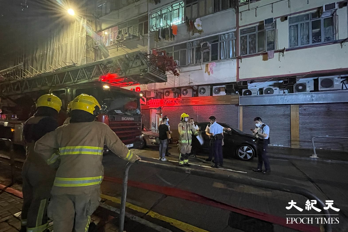 消防將火救熄後，於現場調查起火原因。警員向現場街坊了解事發經過。（卓相如／大紀元）