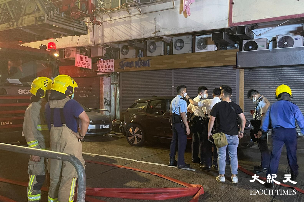 消防將火救熄後，於現場調查起火原因。警員向現場街坊了解事發經過。（卓相如／大紀元）