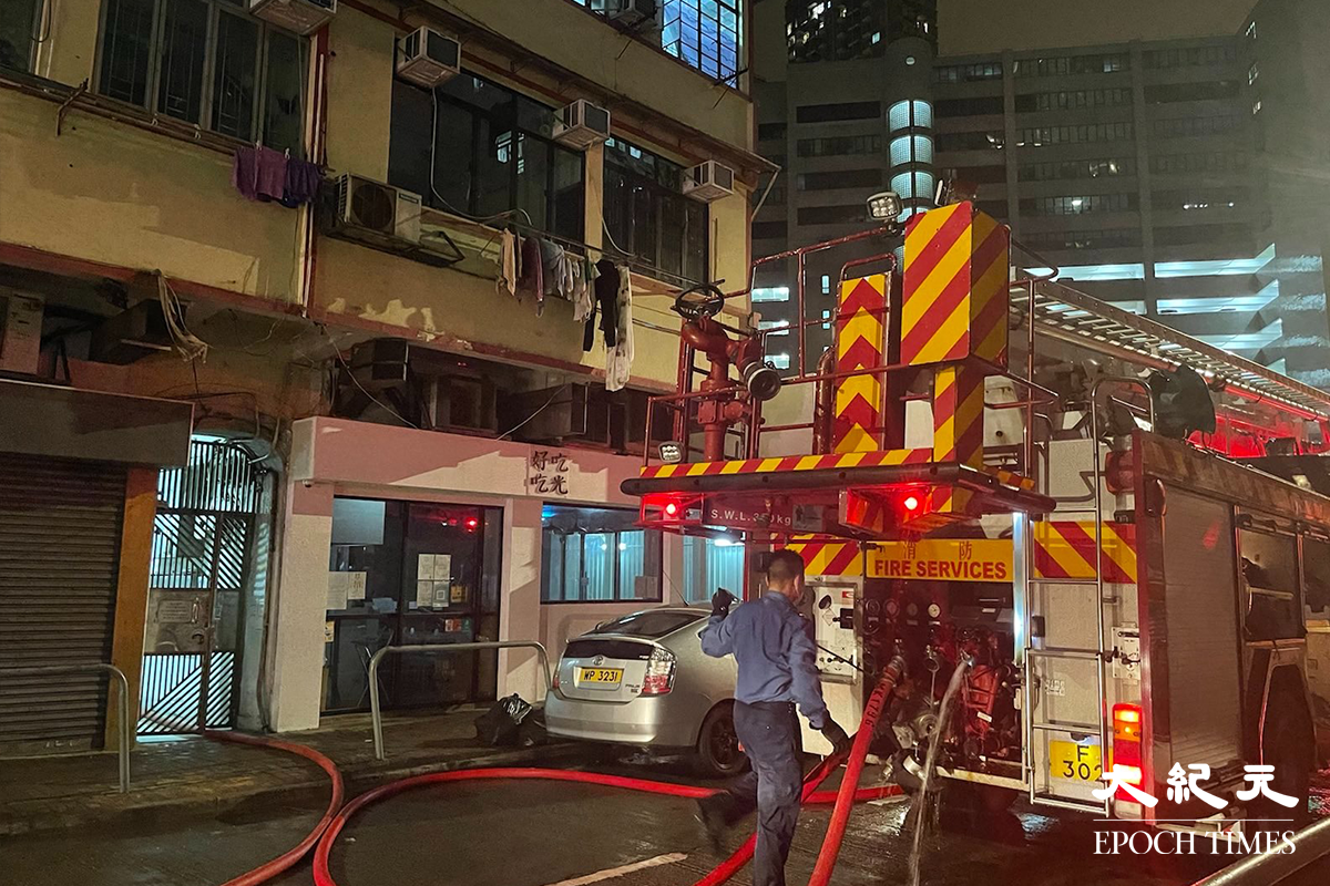消防將火救熄後，於現場調查起火原因。警員向現場街坊了解事發經過。（卓相如／大紀元）